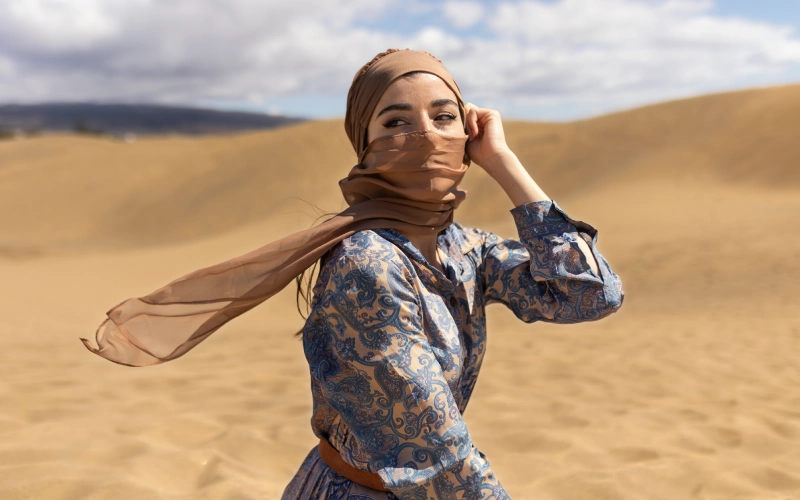 Woman in headscarf standing in desert