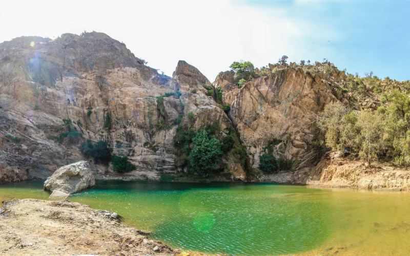 Scenic view of rocky cliffs and green water at Abha waterfall in Saudi Arabia
